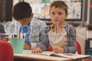 School kids drawing on notebook in classroom