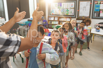 School kids standing and forming a queue in classroom at school