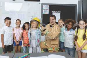 Happy students standing with firefighter in classroom