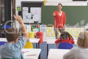 Teacher asking question to a schoolboy in classroom