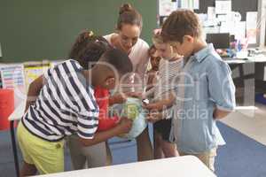 Schoolteacher explaining to his school kids the earth globe in classroom