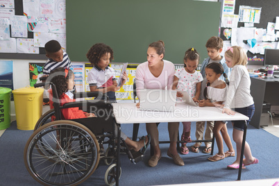 School kids using digital tablet while teacher interacting with students at school