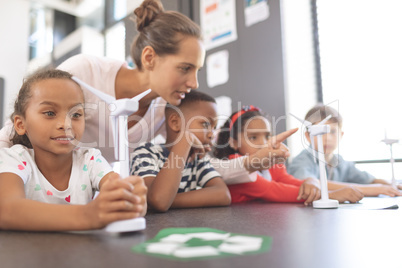 Teacher explaining about windmill to school kids at school in classroom