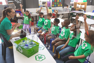 School kids wearing recycle tee-shirt raising hand to answer at a question
