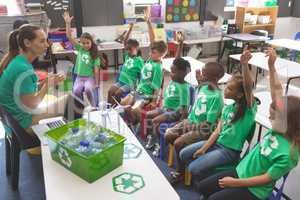School kids wearing recycle tee-shirt raising hand to answer at a question