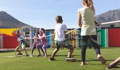 Group of school kids playing tug of war