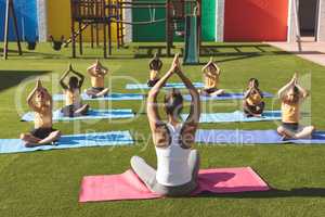 Trainer teaching yoga to students in school playground