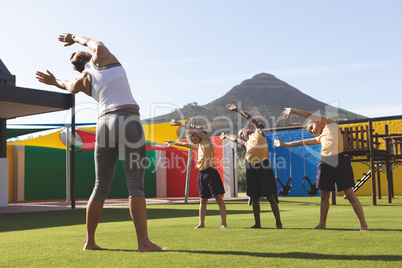 Trainer teaching yoga to students in school playground