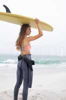 Female surfer carrying surfboard on her head at beach