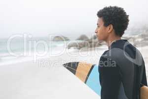 Male surfer holding surfboard on the beach