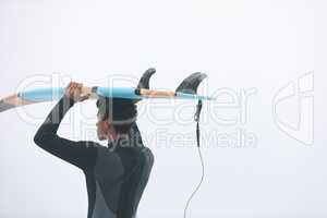 Male surfer carrying surfboard on her head at beach