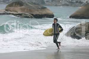 Male surfer holding surfboard while running on beach