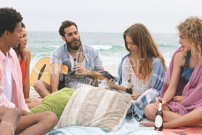 Woman using mobile phone while fiends interacting on beach