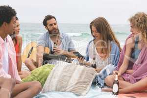 Woman using mobile phone while fiends interacting on beach