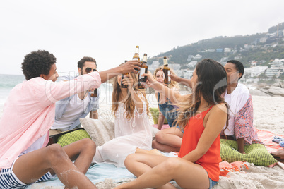 Group of friends toasting with beer bottles on beach