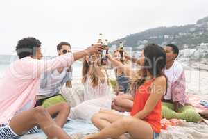 Group of friends toasting with beer bottles on beach