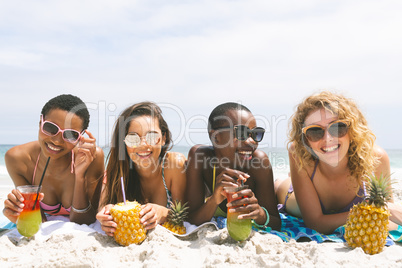 Women lying at beach while having pineapple juice Women lying at beach while having pineapple juice