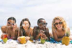Women lying at beach while having pineapple juice