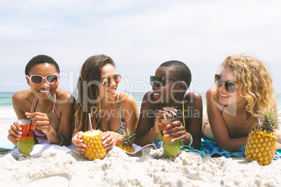 Women lying at beach while having pineapple juice