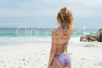 Woman standing with hand on hair on beach