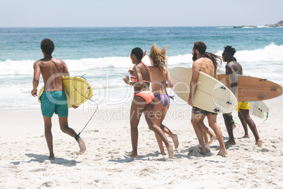 Group of friends holding surfboard at beach