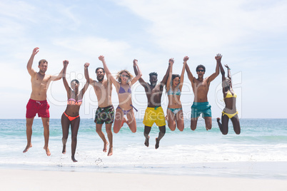 Group of friends enjoying and jumping in water at beach