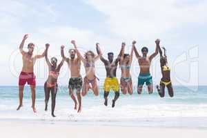 Group of friends enjoying and jumping in water at beach