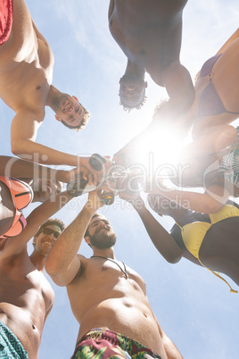 Group of muulti-ethnic friends toasting with beer bottle at beach