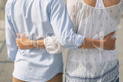 Caucasian couple  standing on the promenade with arm around on a sunny day