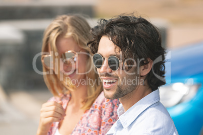 Happy Caucasian couple with sun glasses standing on beach promenade