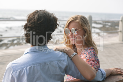 Caucasian couple standing on the promenade with arm around on a sunny day
