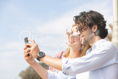 Caucasian couple taking selfie while standing at beach promenade