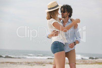 Caucasian couple looking at each other and dancing on beach
