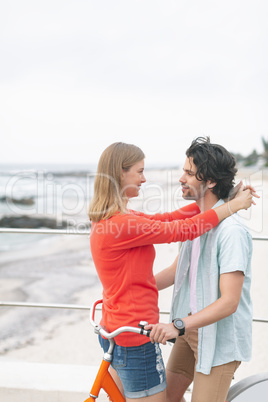 Romantic Caucasian couple embarrassing each other on cycle at beach