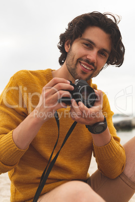 Caucasian man using digital camera on beach
