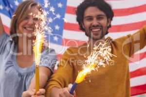 Caucasian couple playing with fire cracker while holding american flag