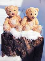 two small teddy bears are sitting on a stump