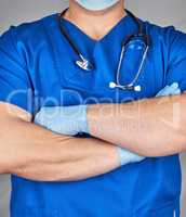 doctor in blue uniform and latex gloves crossed his arms over hi