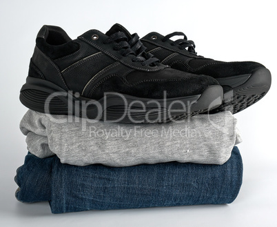 stack of clothes jeans, sweater and black pair of men's shoes