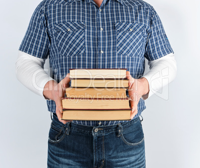 man in blue plaid shirt holding a stack of books
