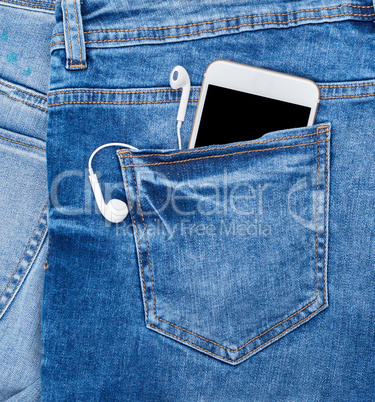 white smartphone with headphones in the back pocket of blue jean