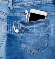 white smartphone with headphones in the back pocket of blue jean