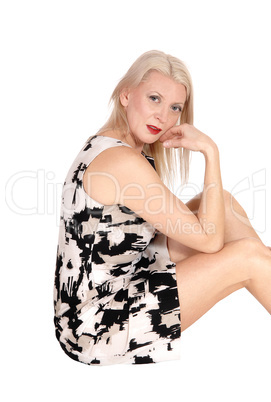 Pretty blond woman sitting on the floor, looking