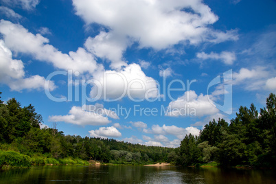 Landscape with river, forest and blue sky.