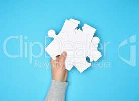 female hand holding a stack of large white paper puzzles