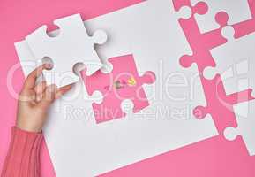 female hand puts white big puzzles on a pink background, the ins