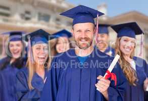 Proud Male Graduate in Cap and Gown In Front of Other Graduates