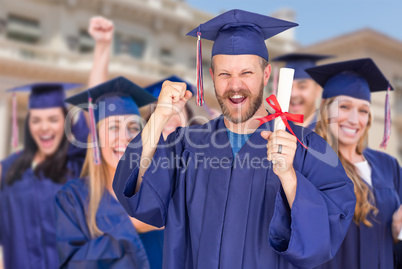 Proud Male Graduate in Cap and Gown In Front of Other Graduates