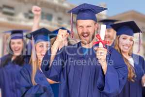 Proud Male Graduate in Cap and Gown In Front of Other Graduates