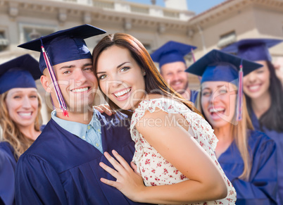 Proud Male Graduate In Cap and Gown with Girl Among Other Graduates